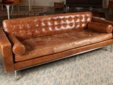 un canapé en cuir marron posé sur un tapis dans un salon