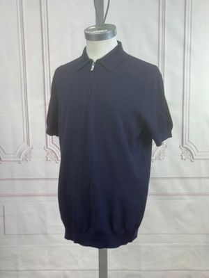 un polo bleu marine posé sur un mannequin devant un mur blanc