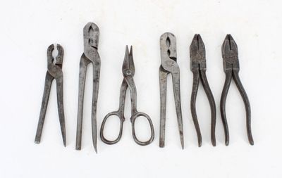 five pairs of pliers and a pair of scissors on a white surface