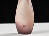 a pink vase with a flower in it sitting on a table