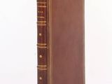 an old book with a brown cover sitting on top of a table