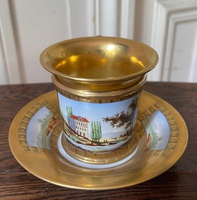 a gold cup and saucer sitting on a wooden table