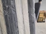 de nombreux rouleaux de matelas posés à même le sol dans un entrepôt