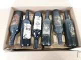 Plusieurs bouteilles de vin se trouvent dans une boîte en carton posée sur une surface blanche.