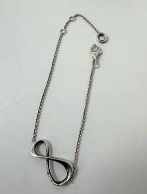 a close up of a silver necklace on a white surface