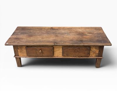 une vieille table basse en bois surmontée de deux tiroirs