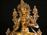 a gold statue of a woman sitting on top of a table