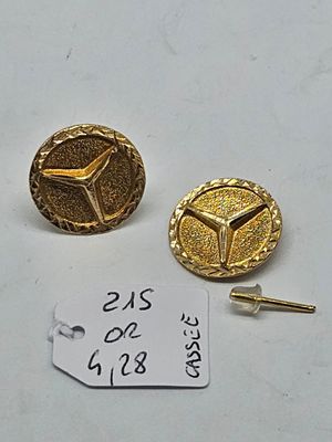 two gold colored buttons and a key on a white surface