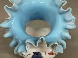 a blue vase with a bird on it on a table