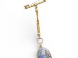 a close up of a gold plated necklace with a blue stone