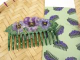 a green comb with purple flowers on it sitting on a table