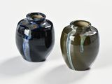 two vases sitting next to each other on a white surface