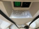 a close up of a white toilet with a green button