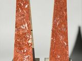 pair of red marble obelisks with black bases on stands
