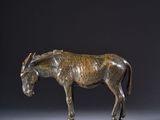 a bronze statue of a horse standing on top of a wooden base