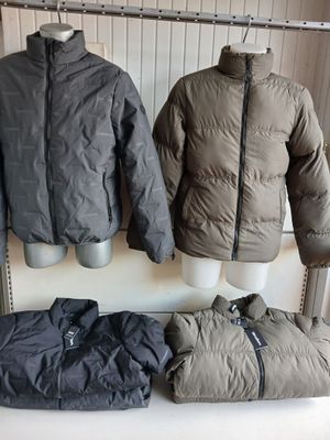 two jackets and a bag sitting on a table in front of a radiator