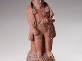 figurine représentant un homme coiffé d'un chapeau et vêtu d'un manteau, tenant un oiseau dans ses mains