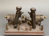 a metal sculpture of two fish on a wooden stand