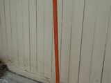 an orange pole that is leaning against a white wall