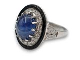 gros plan d'une bague avec une pierre bleue entourée de diamants