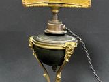 an old fashioned lamp with a golden shade on top of it