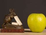 a statue of a mouse and an apple on a table