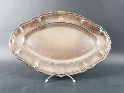 a large silver plate with a decorative design on a stand