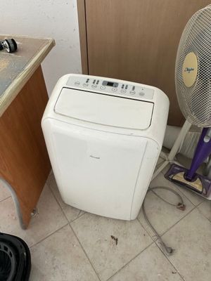 a small white air conditioner sitting next to a fan