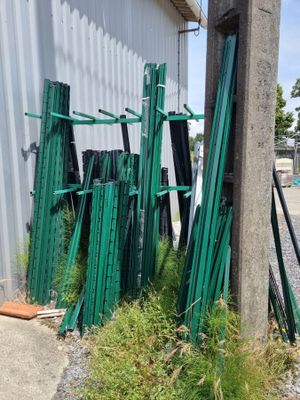 un tas de poteaux de clôture verts à côté d'un bâtiment