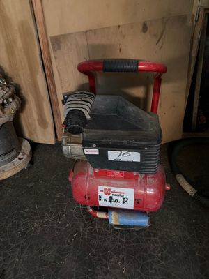 a red air compressor sitting on the floor next to a fire hydrant