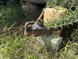 an old rusted water tank sitting in the grass next to a boat