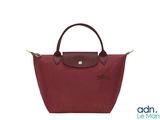 un sac Longchamp rouge avec une poignée marron