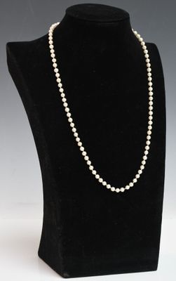 a white pearl necklace on a black mannequin