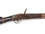 un vieux fusil exposé sur une surface blanche
