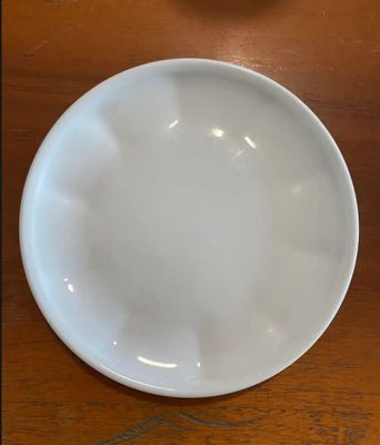 a white plate sitting on a wooden table next to an orange