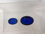 two blue buttons in a clear box on a white surface