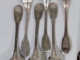 six silver spoons and a spoon rest on a white surface