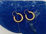un gros plan sur une paire de boucles d'oreilles créoles en or sur une pierre bleue