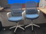 two blue office chairs sitting in front of a computer desk