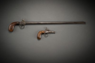 an old gun and a revolver on a gray background