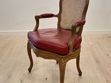 une chaise en bois avec une assise en cuir rouge, posée sur un parquet en bois dur