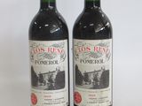 two bottles of red wine sitting next to each other on a white surface