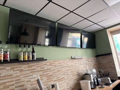 a picture of a kitchen with two televisions on the wall
