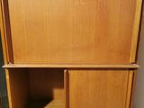 a wooden cabinet with two shelves and a door in the background