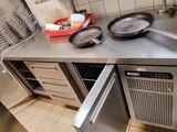 plan de travail en acier inoxydable dans une cuisine professionnelle, avec deux poêles et un lave-vaisselle