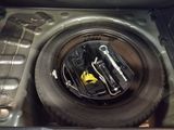 a tire in the trunk of a car with tools in it