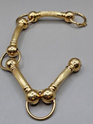 gros plan d'un bracelet en or sur une surface grise