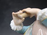 une figurine représentant une femme en robe bleue tenant un morceau de pain