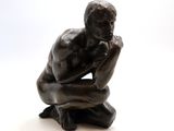 statue of a man sitting on a rock with his hand on his chin