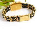 a close up of a gold and black bracelet on a white surface